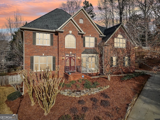 view of front of home featuring fence, brick siding, french doors, and a shingled roof