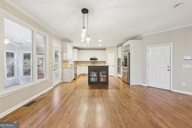 kitchen featuring tasteful backsplash, light wood-style flooring, stainless steel appliances, and ornamental molding