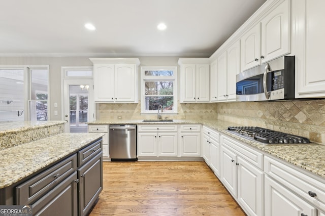 kitchen featuring a sink, appliances with stainless steel finishes, crown molding, and white cabinetry