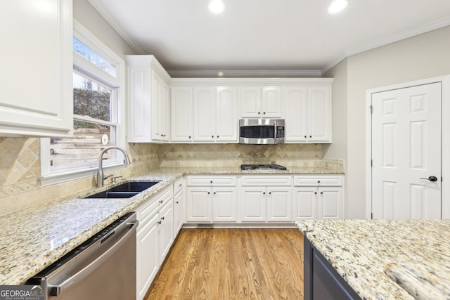 kitchen with a sink, stainless steel appliances, white cabinets, and crown molding