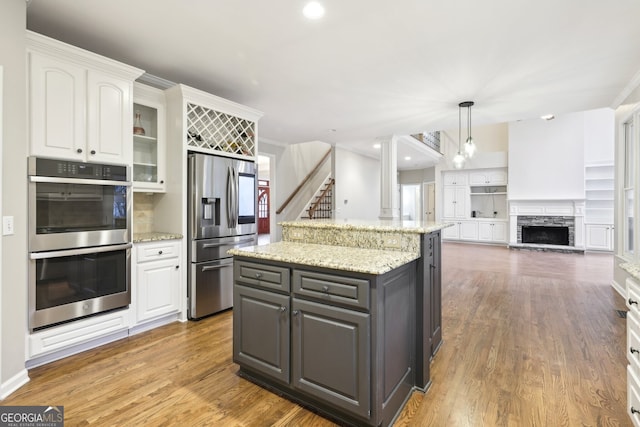 kitchen with stainless steel appliances, glass insert cabinets, white cabinets, and a center island