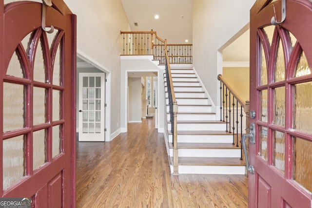 entryway featuring stairway, wood finished floors, baseboards, a high ceiling, and recessed lighting