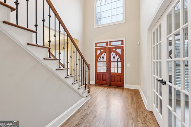 entryway with wood finished floors, french doors, stairway, a high ceiling, and baseboards