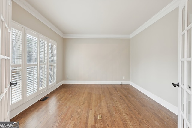 unfurnished room featuring crown molding, baseboards, and wood finished floors