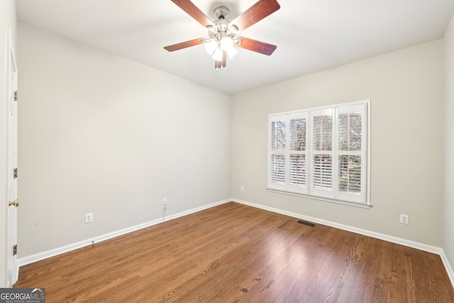 spare room featuring visible vents, ceiling fan, baseboards, and wood finished floors