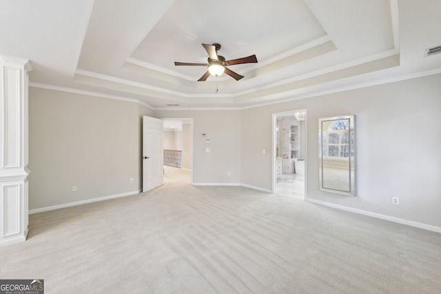 spare room with a tray ceiling, light carpet, baseboards, and a ceiling fan