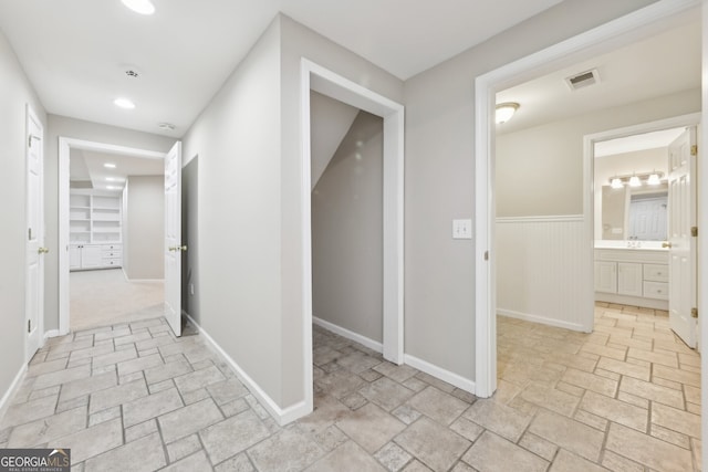 corridor featuring visible vents, baseboards, wainscoting, recessed lighting, and stone finish floor