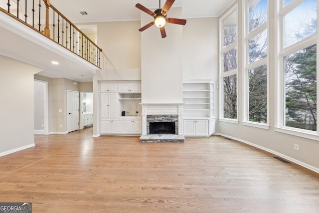 unfurnished living room featuring light wood-type flooring, a fireplace, visible vents, and baseboards