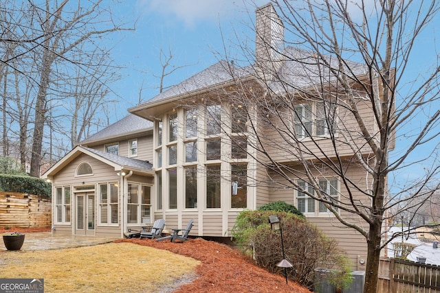 rear view of property featuring a patio, fence, french doors, a shingled roof, and a chimney