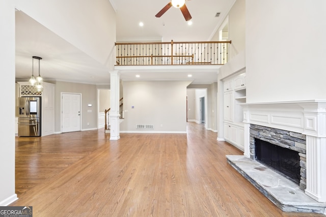 unfurnished living room with light wood finished floors, visible vents, baseboards, a fireplace, and a ceiling fan