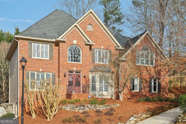 view of front facade featuring brick siding and a shingled roof