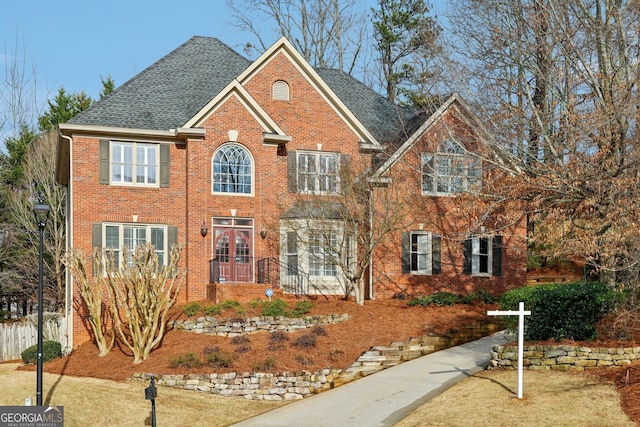 view of front facade featuring french doors, brick siding, and roof with shingles