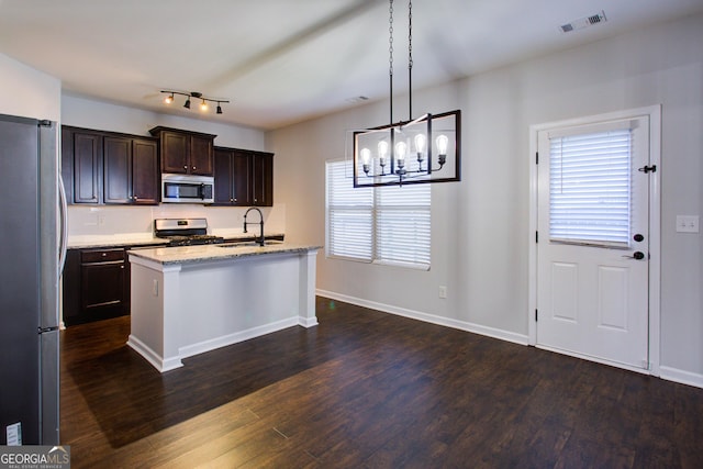 kitchen with decorative light fixtures, a center island with sink, visible vents, appliances with stainless steel finishes, and a sink