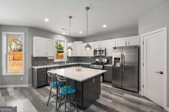 kitchen with a sink, white cabinetry, light countertops, appliances with stainless steel finishes, and a kitchen bar