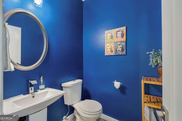 bathroom with a sink, toilet, and baseboards