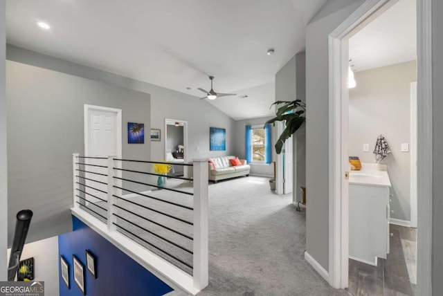 corridor with an upstairs landing, carpet, vaulted ceiling, and baseboards