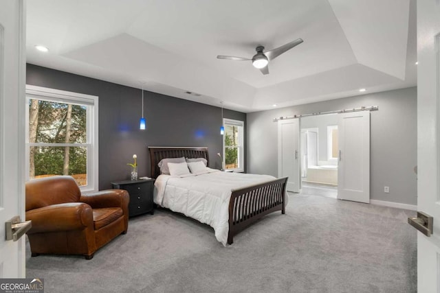 carpeted bedroom featuring ensuite bathroom, a barn door, recessed lighting, baseboards, and a raised ceiling