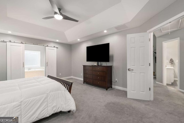 bedroom featuring light carpet, a barn door, attic access, a tray ceiling, and recessed lighting