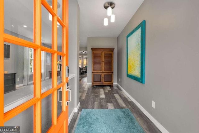 corridor featuring baseboards and dark wood-style flooring