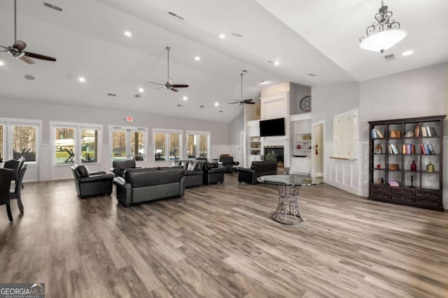 living room with visible vents, high vaulted ceiling, a fireplace, and light wood-style flooring