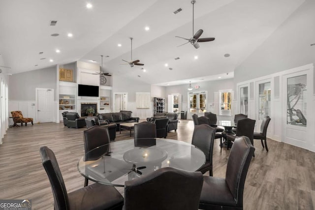 dining room with high vaulted ceiling, light wood-style flooring, a fireplace, and visible vents