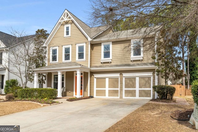 view of front facade featuring driveway, a garage, fence, and a porch