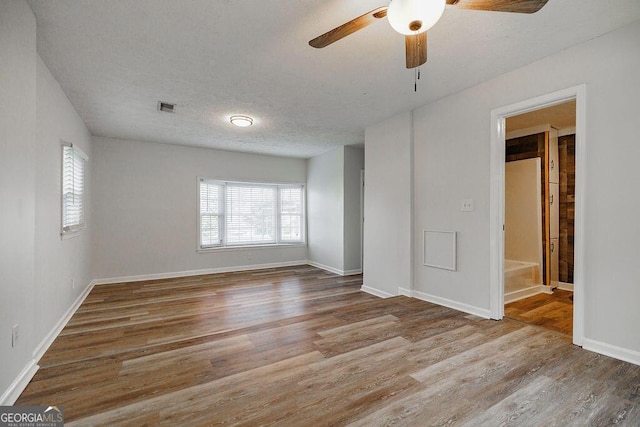 unfurnished room with baseboards, a textured ceiling, visible vents, and wood finished floors