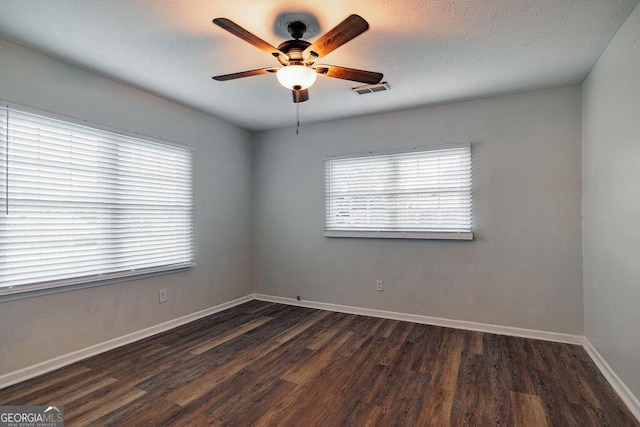 unfurnished room with ceiling fan, dark wood-style flooring, visible vents, and baseboards