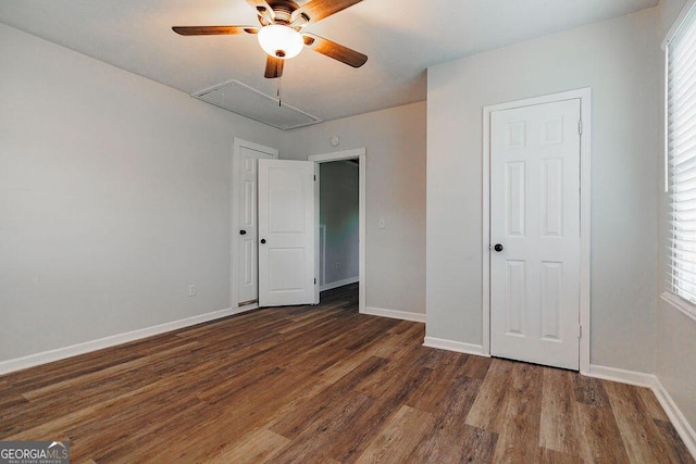 unfurnished bedroom with multiple windows, dark wood-style flooring, attic access, and baseboards