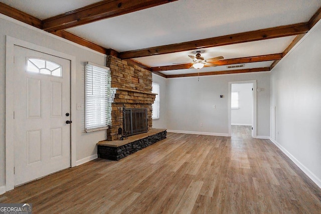 unfurnished living room with a stone fireplace, light wood-type flooring, visible vents, and baseboards