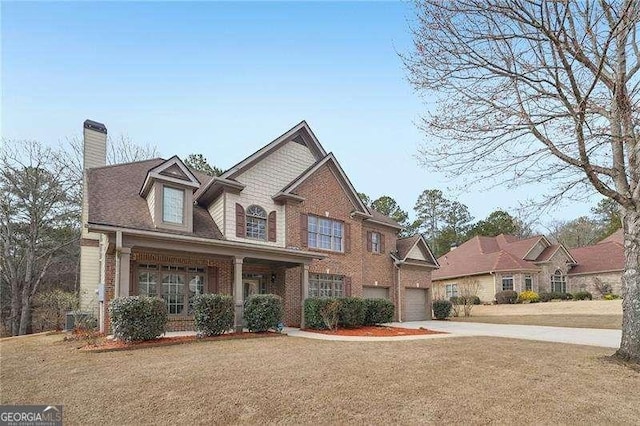 view of front facade with driveway, brick siding, a chimney, and a front yard