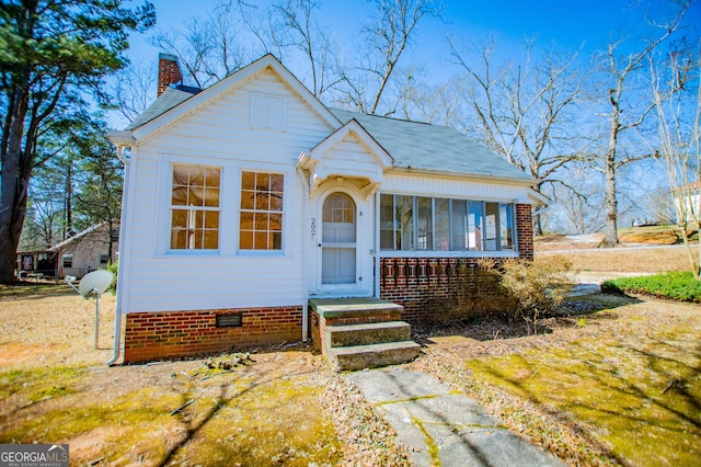 bungalow-style home with crawl space, a sunroom, a shingled roof, and a chimney