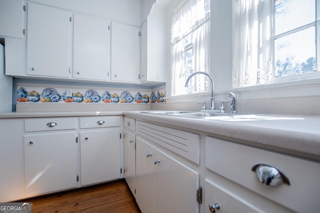 kitchen with light countertops, dark wood-style flooring, a sink, and white cabinetry