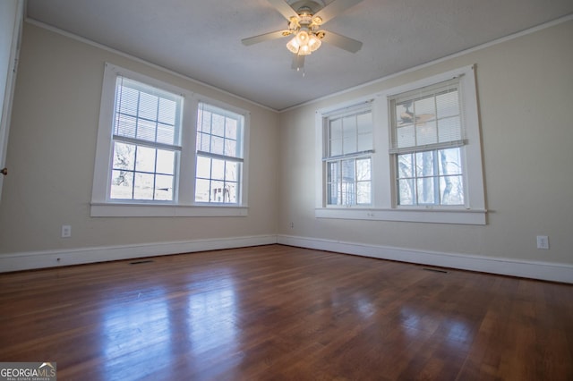 empty room featuring ornamental molding, dark wood-type flooring, and baseboards