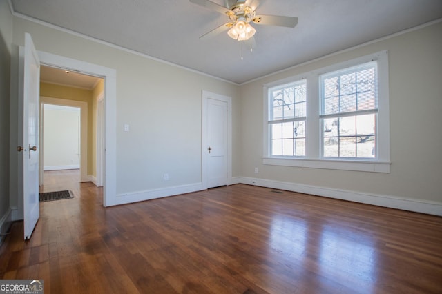 unfurnished bedroom featuring a ceiling fan, baseboards, dark wood-type flooring, and crown molding