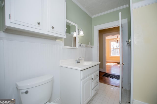 half bathroom featuring tile patterned flooring, crown molding, vanity, and toilet