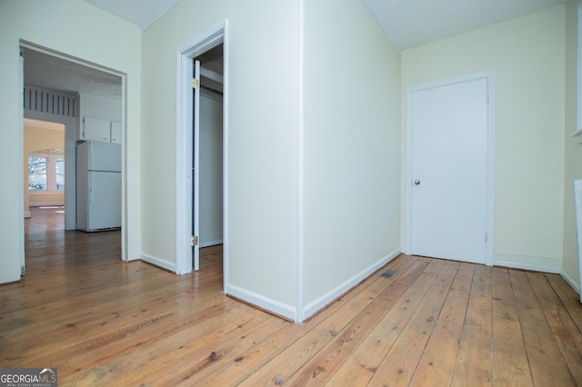 unfurnished bedroom featuring light wood-style floors, baseboards, and freestanding refrigerator