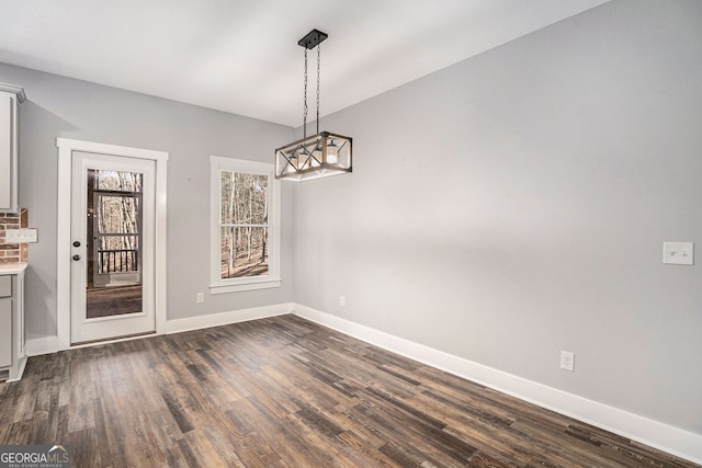 unfurnished dining area featuring dark wood finished floors and baseboards