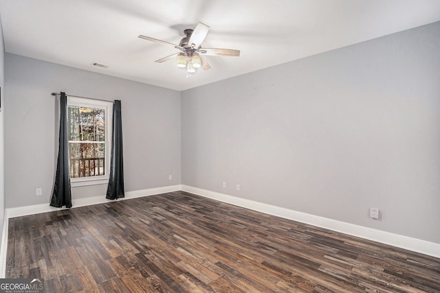 unfurnished room featuring ceiling fan, dark wood finished floors, visible vents, and baseboards