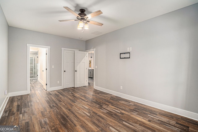 unfurnished bedroom with visible vents, baseboards, dark wood-style flooring, ensuite bathroom, and a closet