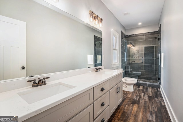 bathroom featuring double vanity, wood finished floors, a sink, and toilet