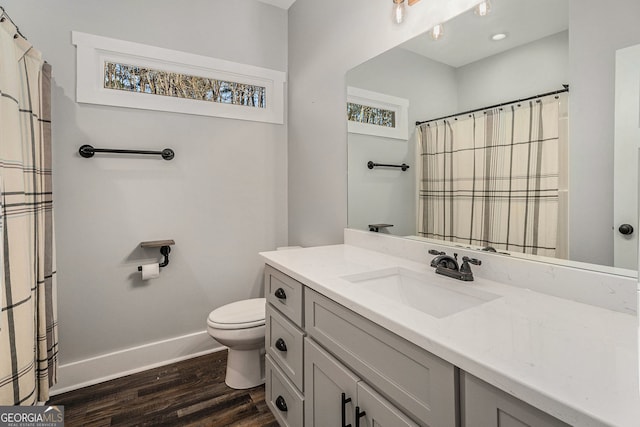 bathroom with toilet, baseboards, wood finished floors, and vanity