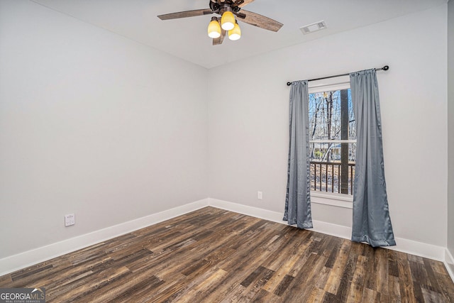 unfurnished room with a ceiling fan, visible vents, dark wood finished floors, and baseboards