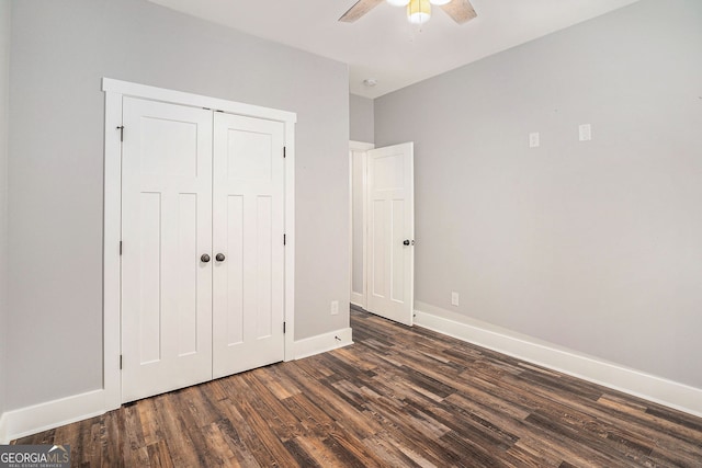 unfurnished bedroom with a ceiling fan, a closet, baseboards, and dark wood-type flooring