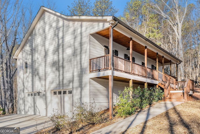 view of property exterior featuring stairs, concrete driveway, an attached garage, and a balcony