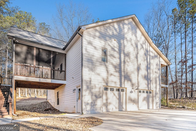 view of side of property with a garage, a sunroom, driveway, and stairs