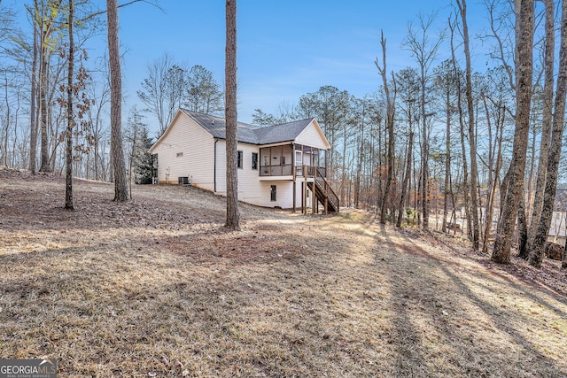 view of side of home featuring a sunroom, stairway, and a deck