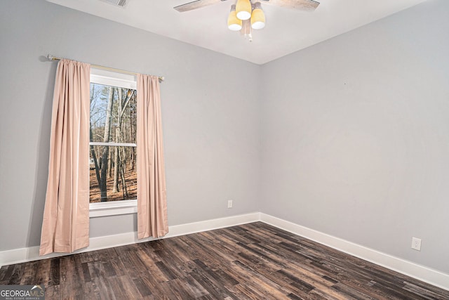 empty room with dark wood finished floors, a ceiling fan, and baseboards