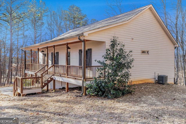 view of side of property with stairs, a porch, and central AC unit