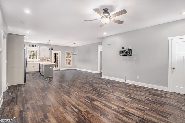 unfurnished living room with baseboards, dark wood finished floors, a ceiling fan, and recessed lighting